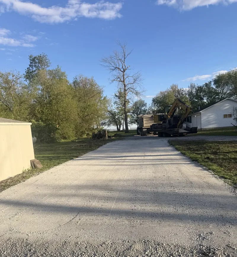 Gravel driveway installation with excavator on site